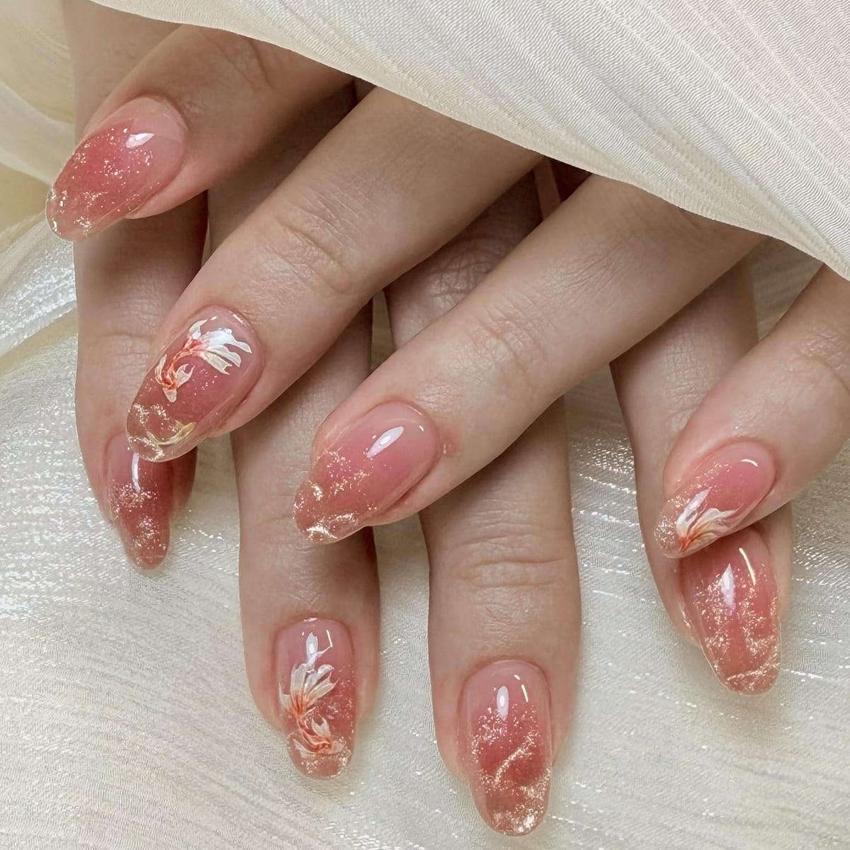 杏仁形珊瑚果冻指甲,缀金箔碎片与手绘锦鲤花卉图案,寓意好运